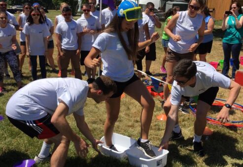 Participants in white shirts engage in a fun and wacky relay challenge during an Outrageous Games team building event, with one person wearing a snorkel mask.