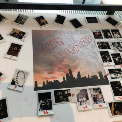 A themed display board titled 'Team Asian Hipsters' from a Polaroid scavenger hunt, featuring a central image of the Chicago skyline at sunset. The board is surrounded by numbered Polaroid photos capturing moments from the scavenger hunt challenges, arranged in a creative and organized layout. The display highlights teamwork and creativity during this engaging and fun-filled team building activity. thumbnail