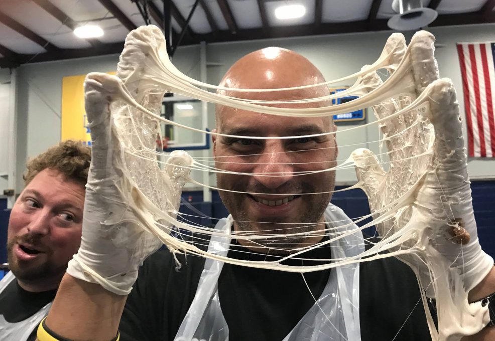 A man wearing gloves stretches melted marshmallow during The Chocolate Challenge team building event.
