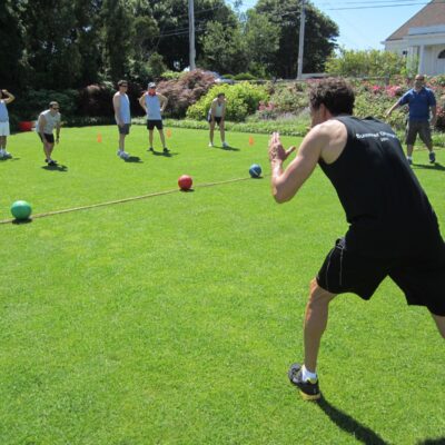 Participants gearing up for a dodgeball challenge during the Outrageous Games team building event on a sunny lawn. thumbnail