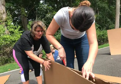 Team members cutting cardboard to construct their boat during the Build-A-Boat team building activity.