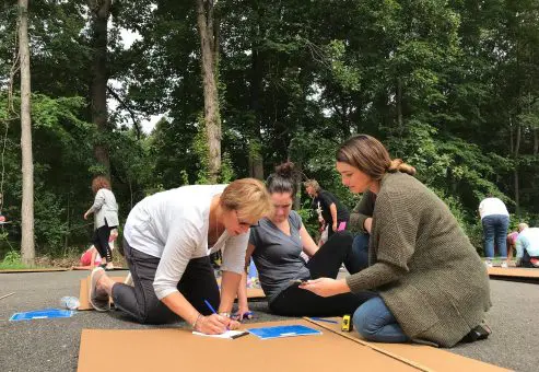 A group of participants collaborating on boat blueprints during the Build-A-Boat team building challenge.
