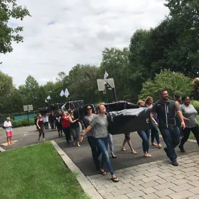 Participants carrying their completed cardboard boats to the water during the Build-A-Boat team building challenge. thumbnail