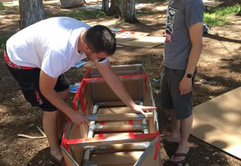 Two participants assembling the structure of a cardboard boat during the Build-A-Boat team building activity.