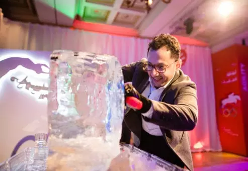 A participant skillfully chisels an ice block during an engaging Team building Ice Sculpting activity, focused on creativity and collaboration.