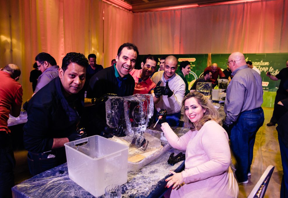 A team enthusiastically works together on their ice sculpting project during a Team building Ice Sculpting event, displaying their creativity and collaboration skills.