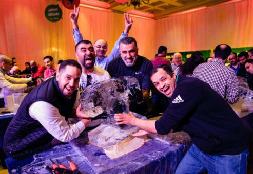 A group of participants eagerly working together to sculpt ice during a Team building Ice Sculpting workshop, showcasing creativity, teamwork, and skill.