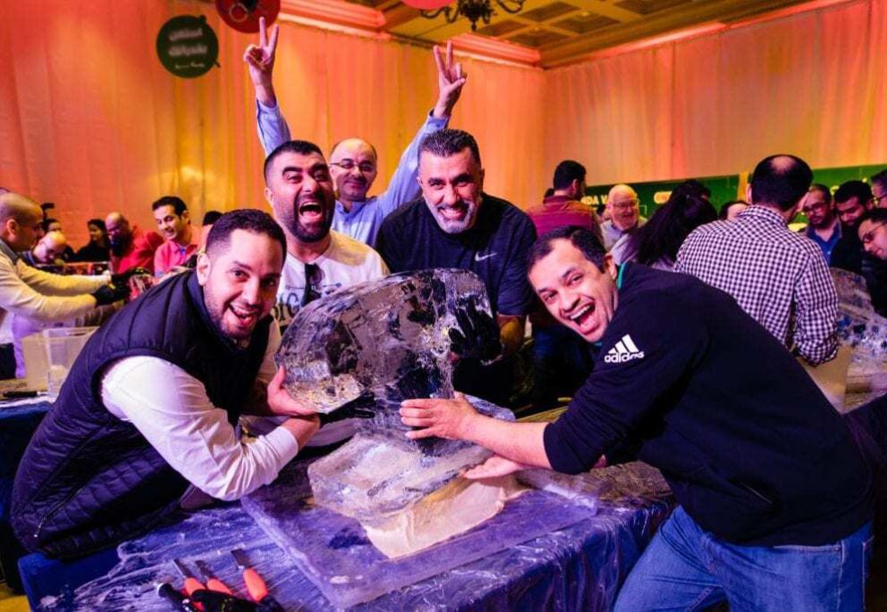 A group of participants eagerly working together to sculpt ice during a Team building Ice Sculpting workshop, showcasing creativity, teamwork, and skill.