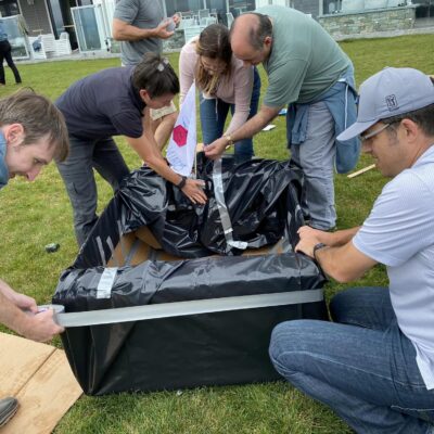 Team members collaborating to construct a cardboard boat during the Build-A-Boat team building activity. thumbnail
