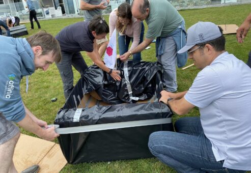 Team members collaborating to construct a cardboard boat during the Build-A-Boat team building activity.