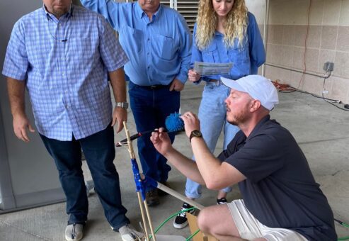 A group of four participants outdoors working together to assemble a small catapult during the Catapult to Success team building activity, emphasizing teamwork, innovation, and hands-on problem-solving.