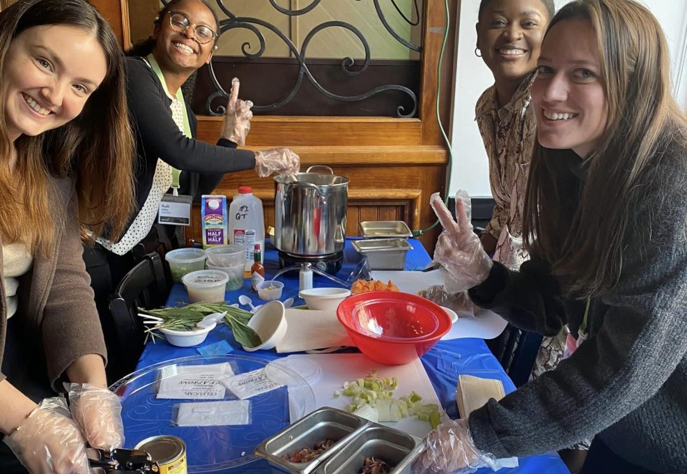 Group of participants smiling while preparing ingredients for the Wicked Good Chowda Cook-Off team building event.