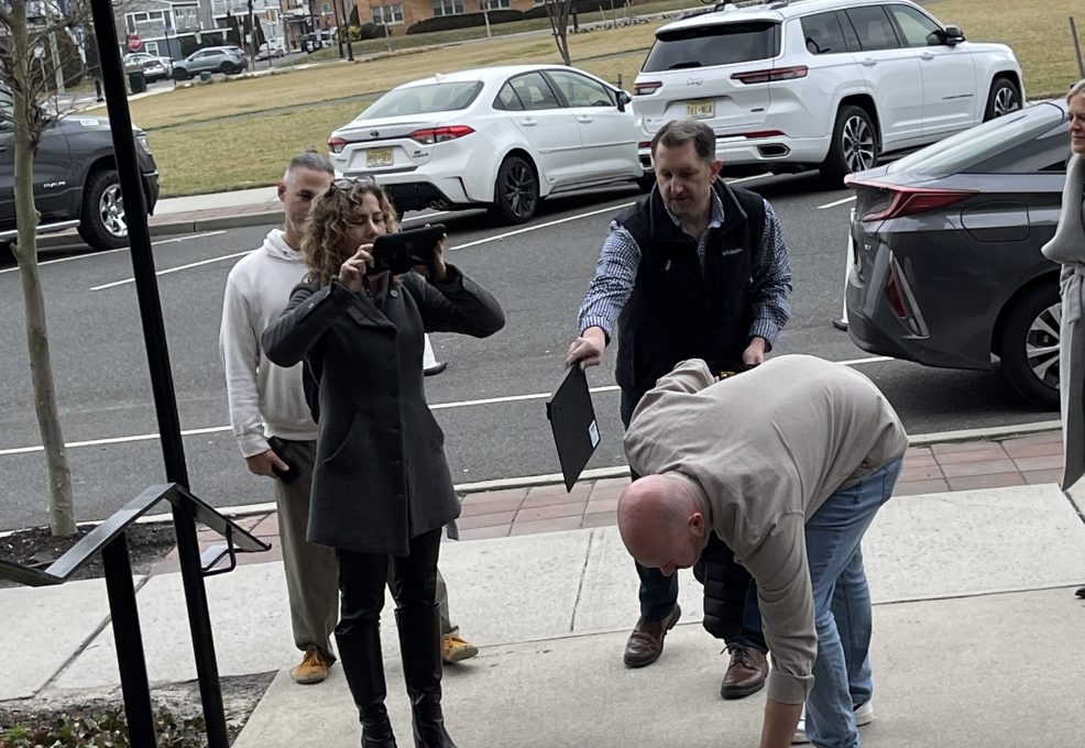 Team members conducting a hands-on outdoor activity, with one person recording one of her team members acting on the Corporate Film Festival team building challenge.
