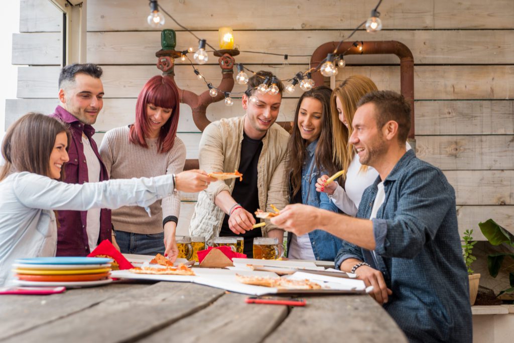 Team members sharing slices of pizza in a relaxed, outdoor setting during The Ultimate Pizza Challenge team building event.