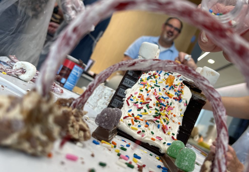A creative chocolate bridge decorated with sprinkles, candy, and licorice arches, built during The Chocolate Challenge team building event. Participants focus on collaboration and edible engineering.