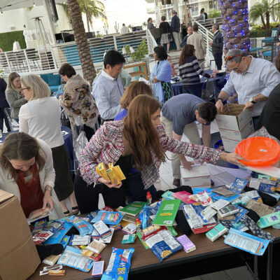 Participants enthusiastically packing care packages for troops during an outdoor Operation Military Care team building event. thumbnail