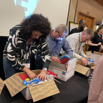 Participants packing care packages with essentials for military personnel, contributing to a rewarding team building experience. thumbnail