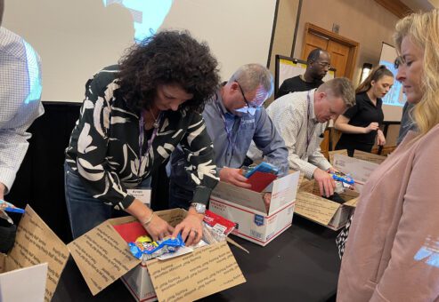 Participants packing care packages with essentials for military personnel, contributing to a rewarding team building experience.
