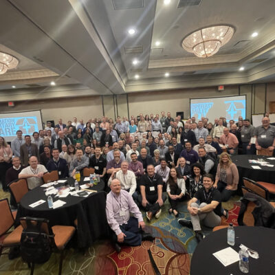A large group gathers together after successfully completing an Operation Military Care team building event, having packed care packages for U.S. troops. thumbnail