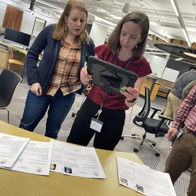 Participants analyze case files and use a tablet to uncover clues during the Corporate CSI team building activity. thumbnail