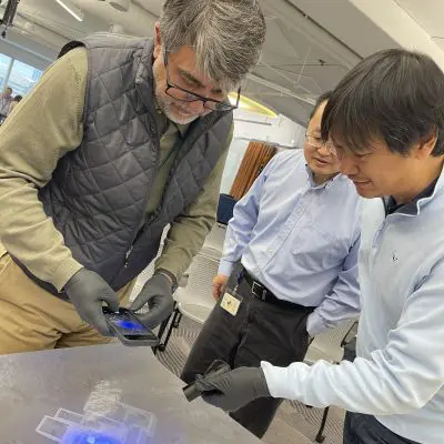 Participants using UV light to inspect a crime scene map during the Corporate CSI team building event.. thumbnail