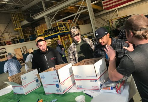Team members collaborating on assembling care packages for U.S. troops during an Operation Military Care team building event.