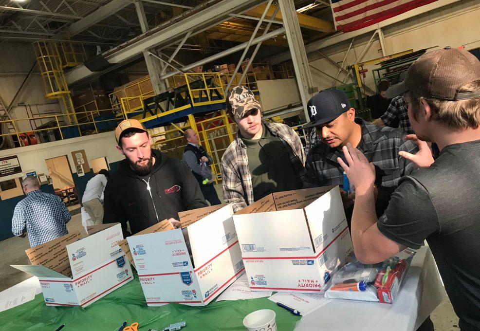 Team members collaborating on assembling care packages for U.S. troops during an Operation Military Care team building event.
