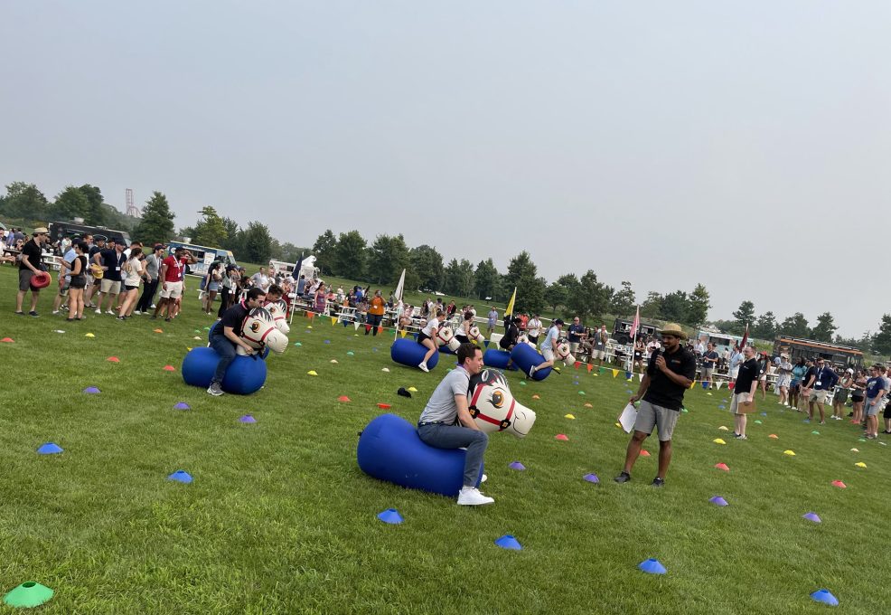 Participants competing in a relay race with inflatable horses during the Outrageous Games team building event.