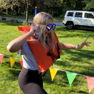 Participant in a life vest and goggles runs through a colorful relay course during an Outrageous Games team building event. thumbnail