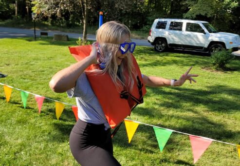 Participant in a life vest and goggles runs through a colorful relay course during an Outrageous Games team building event.