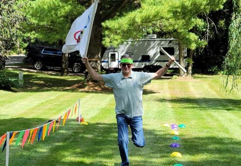 Participant in Outrageous Games team building event celebrates crossing the finish line during a fun, non-athletic relay challenge.