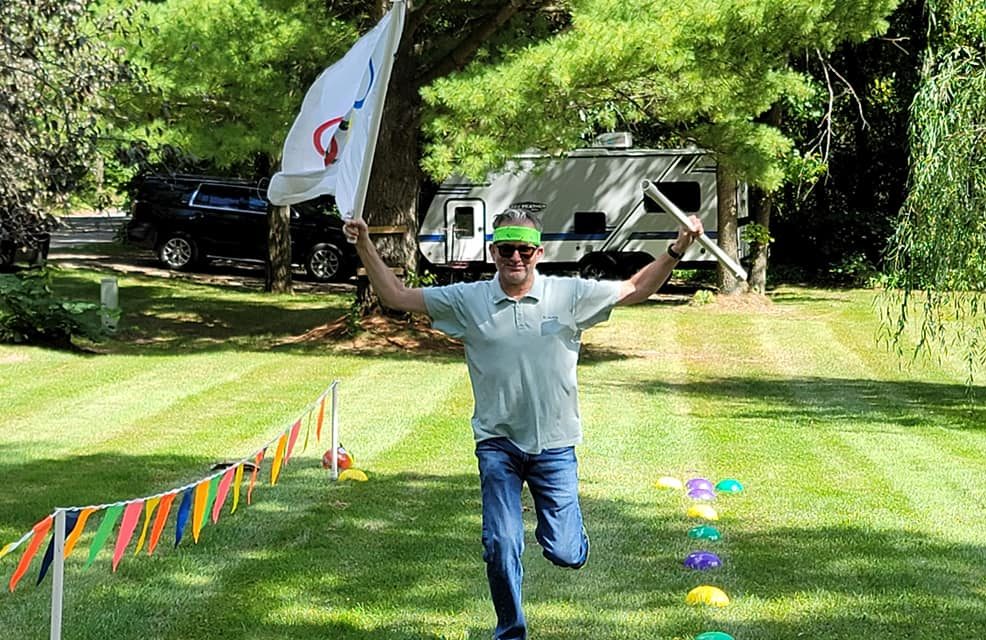 Participant in Outrageous Games team building event celebrates crossing the finish line during a fun, non-athletic relay challenge.