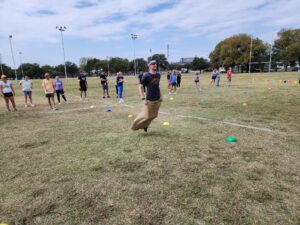 A participant hopping in a sack during a relay race at the Outrageous Games team building event, highlighting fun and teamwork.