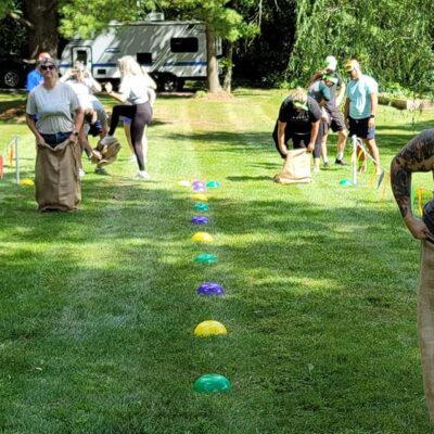 Participants racing in a classic sack race during the Outrageous Games team building event, enjoying friendly competition and teamwork. thumbnail