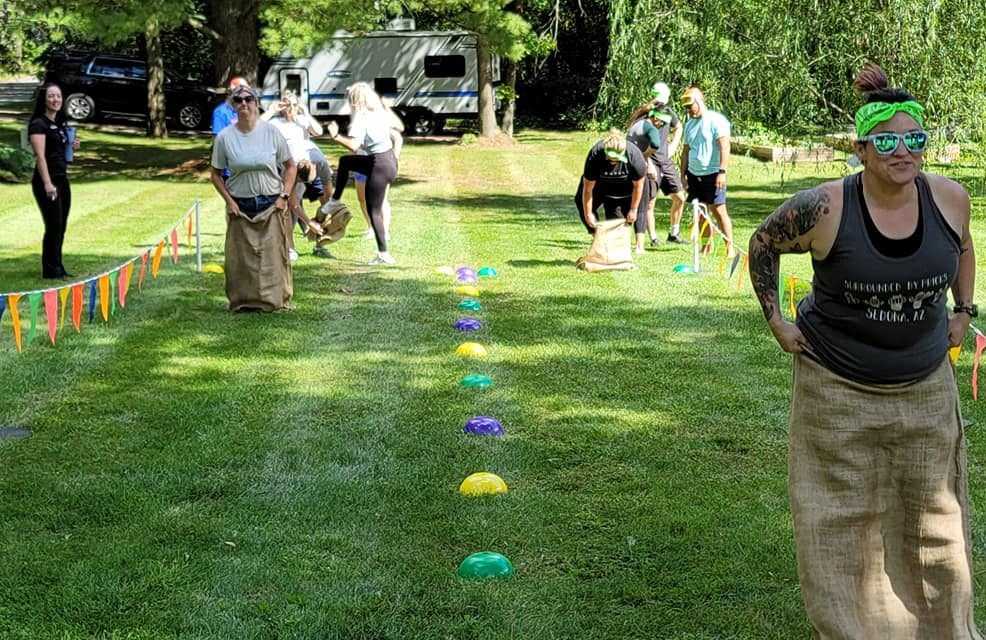 Participants racing in a classic sack race during the Outrageous Games team building event, enjoying friendly competition and teamwork.