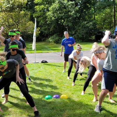 Teams competing in a relay race during the Outrageous Games team building event, fostering collaboration and fun. thumbnail