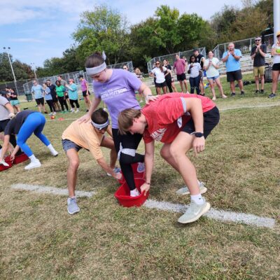 Participants work together to navigate a relay race during the Outrageous Games team building event, encouraging teamwork and problem-solving. thumbnail