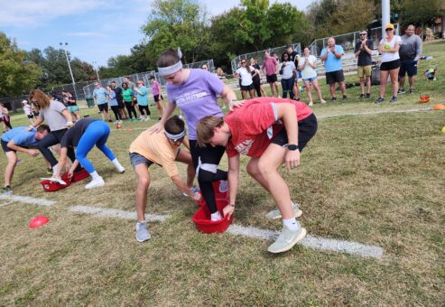 Participants work together to navigate a relay race during the Outrageous Games team building event, encouraging teamwork and problem-solving.