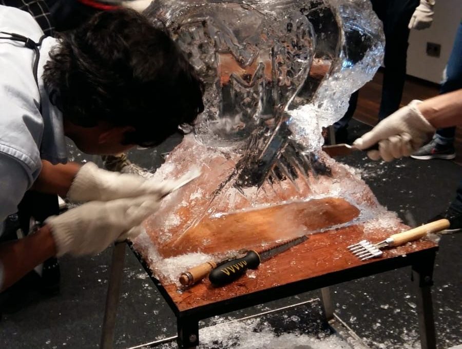 Participants work together to carve an intricate ice sculpture at a Team building Ice Sculpting event, demonstrating collaboration and creativity.