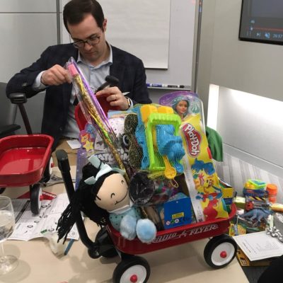 Participant assembling a wagon filled with toys during a charitable holiday team building activity. thumbnail