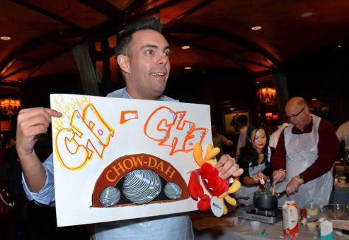 Participant enthusiastically holding a ‘Cha-Cha Chow-dah’ sign during the Wicked Good Chowda Cook-Off team building event.