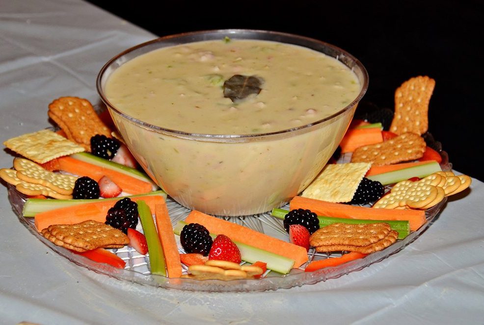 Bowl of chowder surrounded by crackers, fresh vegetables, and berries at the Wicked Good Chowda Cook-Off team building event.