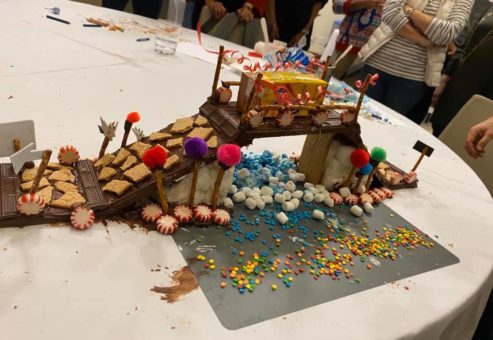 A detailed chocolate bridge created during The Chocolate Challenge team building event. The bridge is decorated with graham crackers, candy, and colorful sprinkles, showcasing creativity and teamwork.