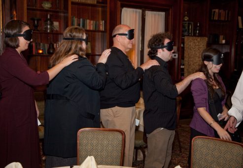 Participants of the Dining in the Dark event forming a human chain while blindfolded, relying on trust and communication as part of a sensory team building experience.