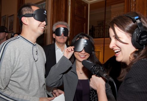 Participants laughing and interacting while wearing blindfolds during a Dining in the Dark team building experience, fostering communication and collaboration through sensory exploration.