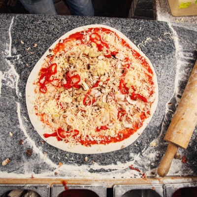 Pizza dough topped with fresh ingredients, ready for baking during The Ultimate Pizza Challenge team building event.