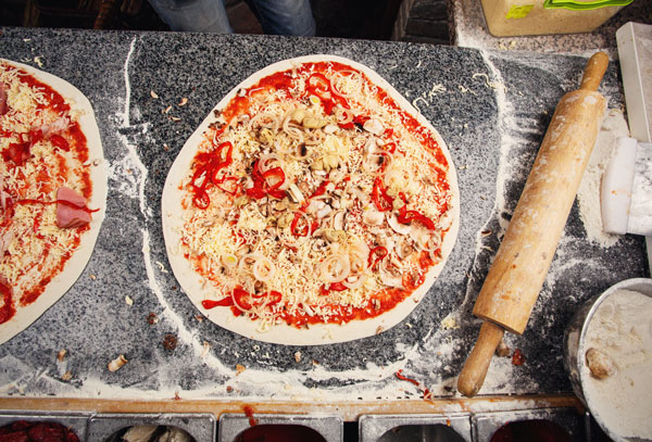 Pizza dough topped with fresh ingredients, ready for baking during The Ultimate Pizza Challenge team building event.