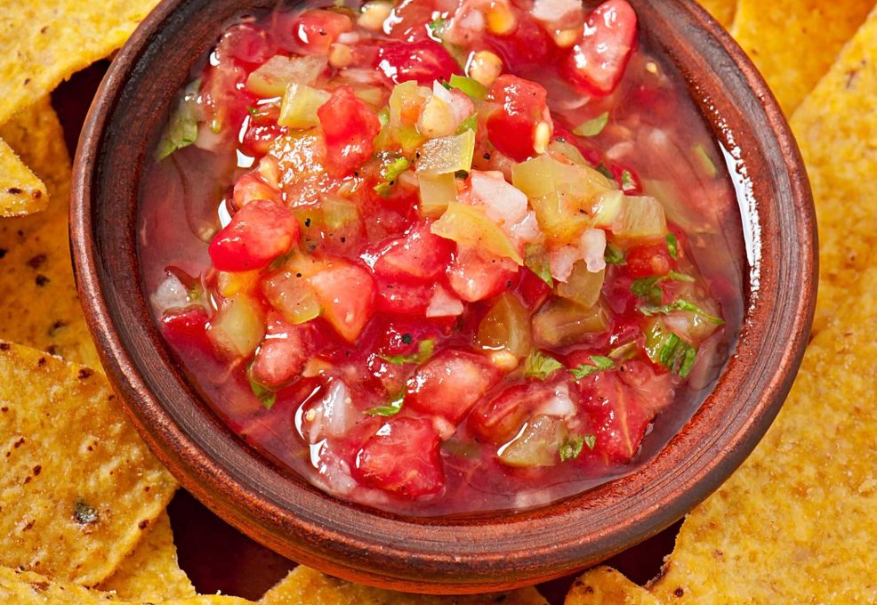 A vibrant bowl of fresh salsa surrounded by crispy tortilla chips, showcasing the flavors created during the Salsa Showdown team building event.