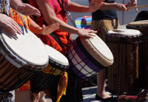 Participants in the Drumming Up A Team event play percussion instruments, collaborating to create a unified rhythm and building team spirit through music and engagement.