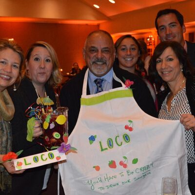 Employees posing for a photo with their Sangria drink and customize apron design.